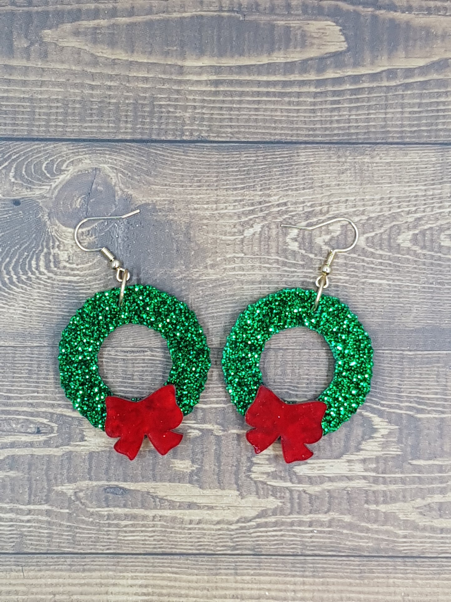 Laser cut acrylic green glitter christmas wreath earring with red bow and finished on a shepherd's hook